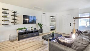 Un salon moderne avec un téléviseur à écran plat, un meuble de rangement noir, une table basse et un canapé.