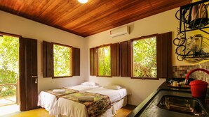 A room with two beds, a wooden ceiling, a kitchen area with a sink, and large windows with wooden shutters. - Pousada Arvoredo (Pirenópolis)