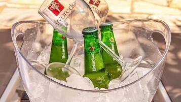 Un balde de vidrio transparente lleno de hielo y tres botellas de cerveza Heineken verdes.