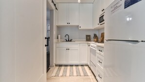 A modern kitchen with white cabinets, a stainless steel refrigerator, and a microwave.