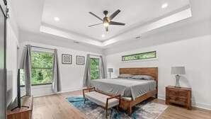 A bedroom with a bed, bedside tables, a ceiling fan, and large windows with curtains. - Top Notch 2 (Atlanta)