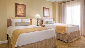A hotel room with two beds, a nightstand with a lamp, and a large window with curtains.