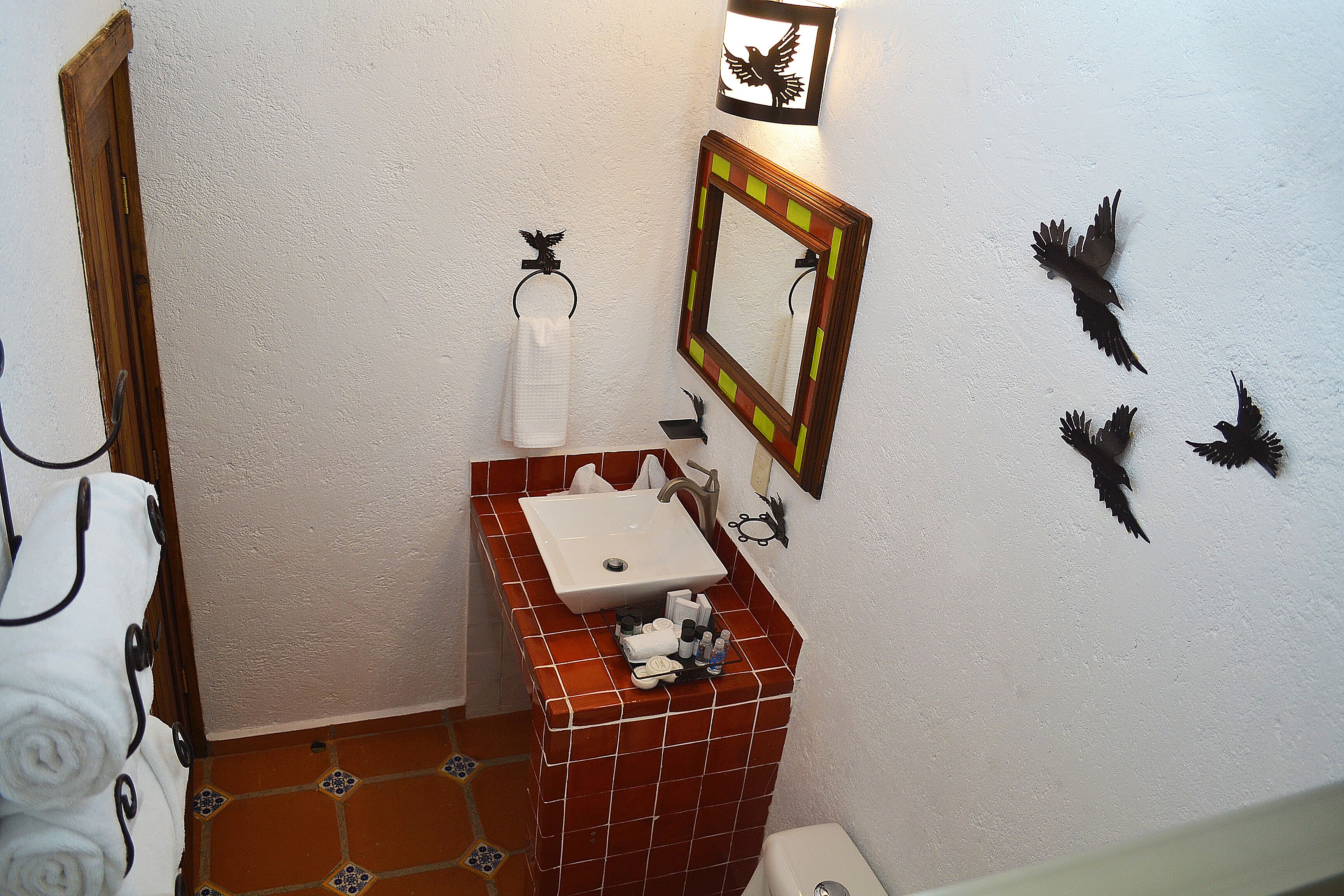 Bany amb un vàser blanc, un mirall i decoració mural.