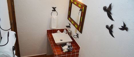 Un baño con un lavabo blanco, un espejo y decoración en la pared.