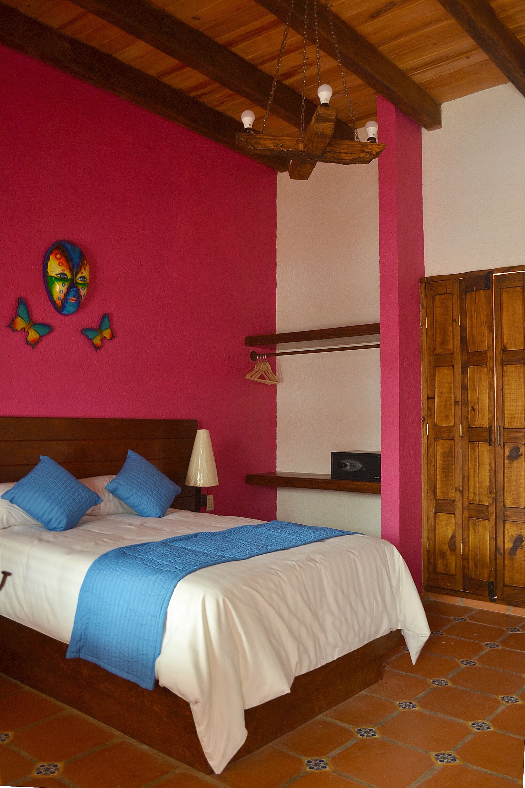 Un dormitorio con una cama de madera, pared rosa y un armario de madera.