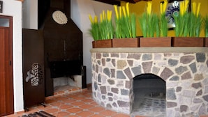 A stone-built fireplace with decorative plants on top, a wooden door, and a tiled floor. - La Casona Pirámides (San Martin de las Pirámides)