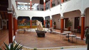 A courtyard with a central sculpture, multiple tables and chairs, and potted plants. - La Casona Pirámides (San Martin de las Pirámides)