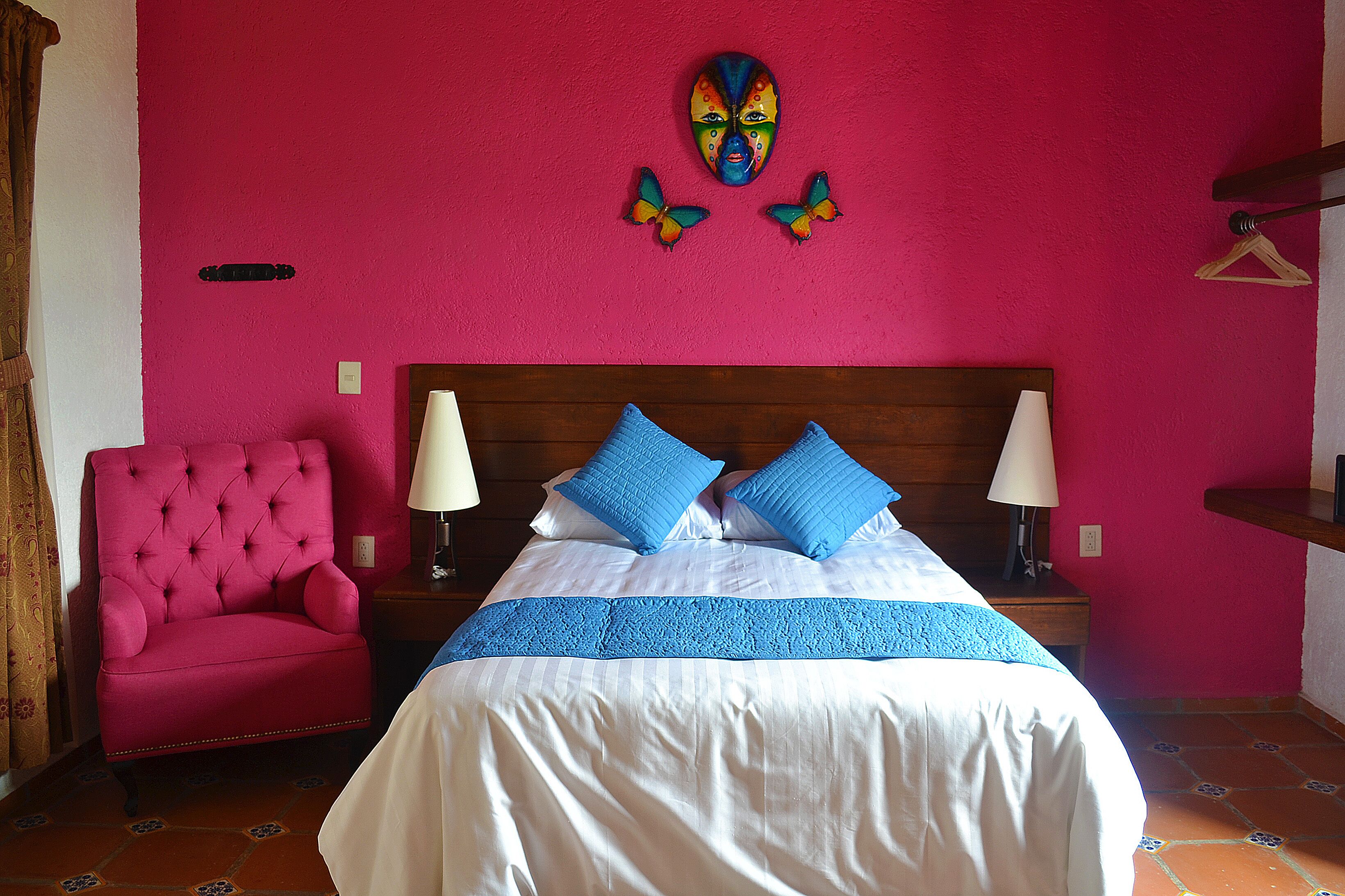 Una habitación con una cama, una silla roja y un cabecero de madera.