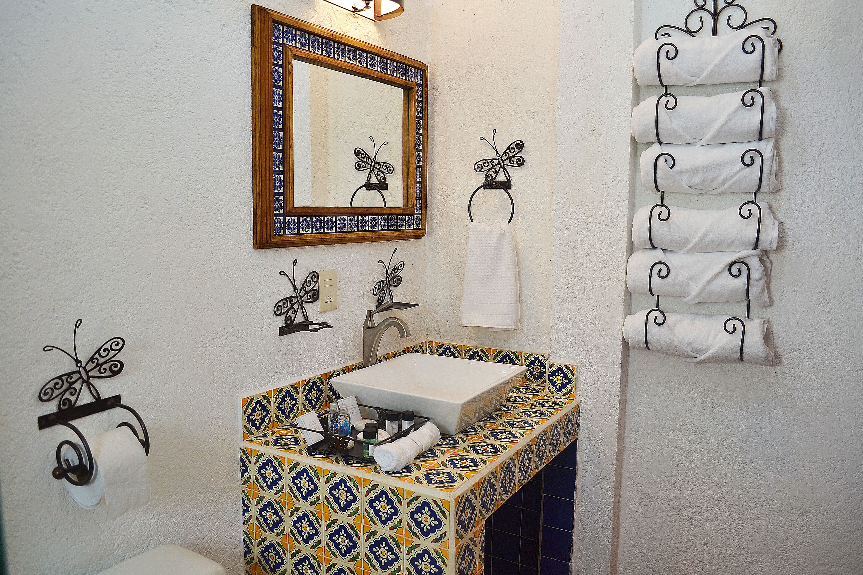 A bathroom with a sink, mirror, and decorative butterfly wall hooks.