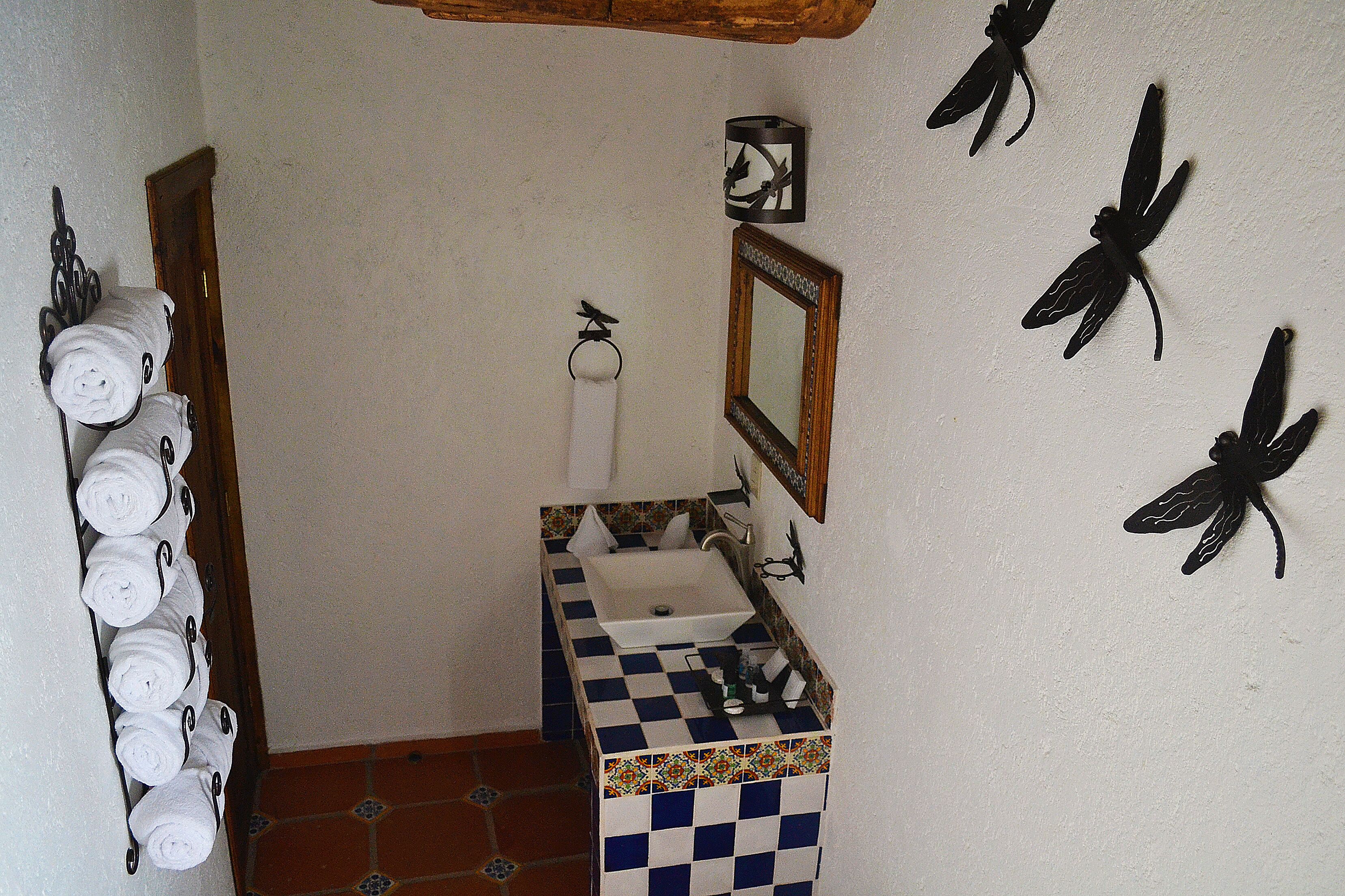 A bathroom with a tiled floor, a sink, a mirror, and towels hanging on a rack.