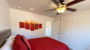 Una camera da letto con un letto, una ventola a soffitto e una parete decorata con opere d'arte.