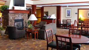 Een hotellobby met een open haard, banken, een eetgedeelte en een bar.