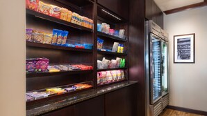 Exposição de petiscos com diversos alimentos embalados e uma área refrigerada.