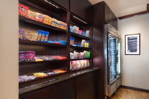 Un présentoir à collations avec divers aliments emballés et un compartiment réfrigéré.