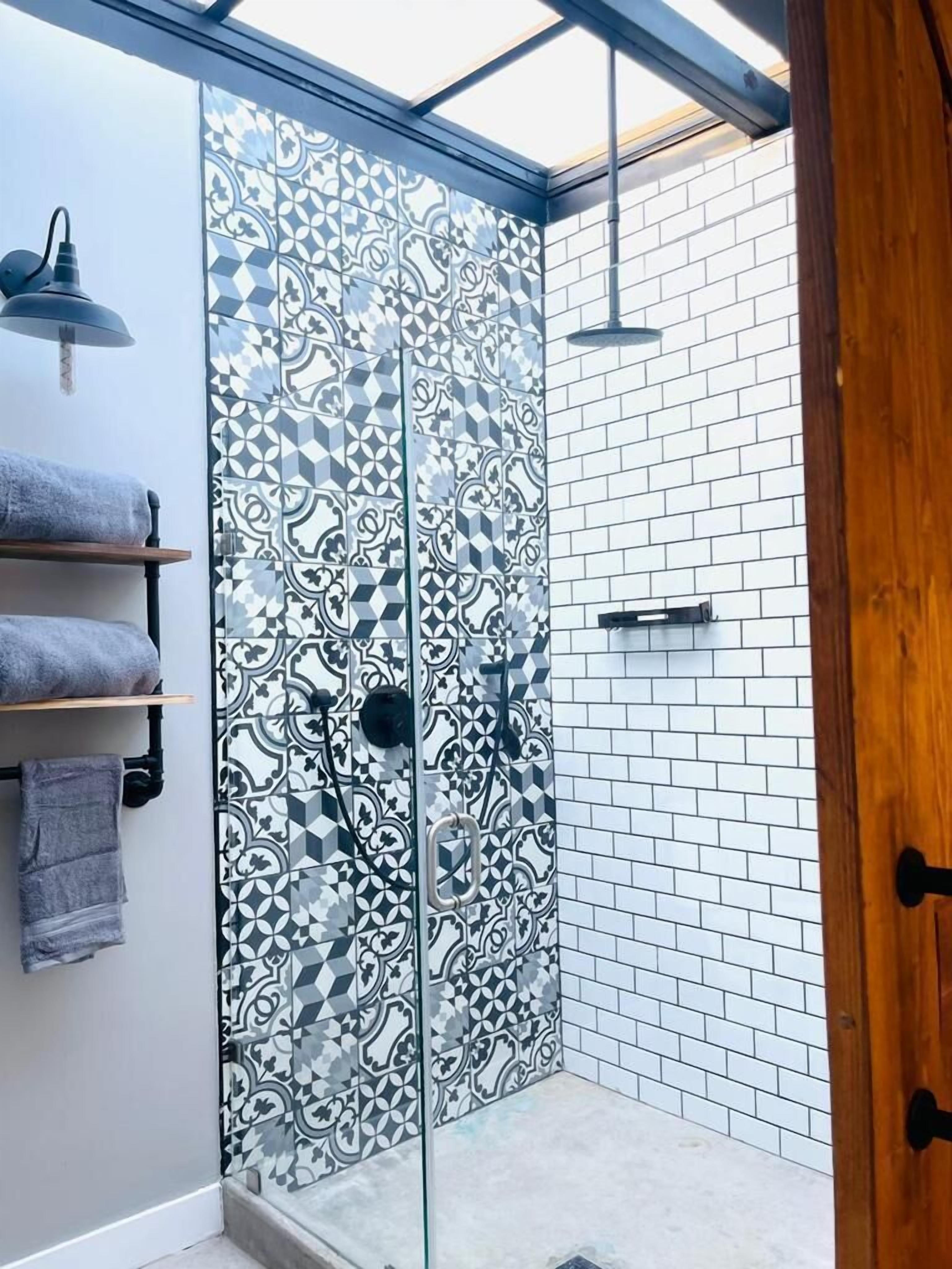 A shower with a patterned glass door, a towel rack with towels, and a wooden door.
