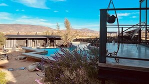 A pool area with a pergola, lounge chairs, and a view of mountains.