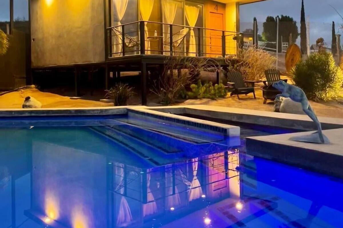 A modern house with a pool, featuring a covered patio and a small deck area.