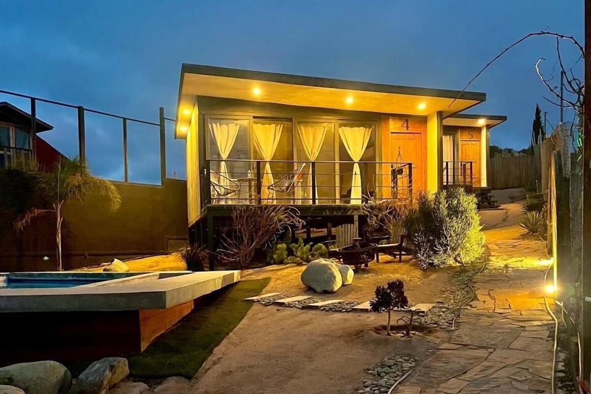 A modern house with a well-lit patio, a swimming pool, and a stone pathway.