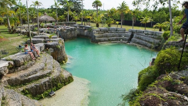 Una piscina naturale circondata da gradini in pietra e rigogliosa vegetazione.