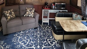 A cozy cabin interior with a wooden ceiling, a sofa, a small table, and a microwave. - The Bunkhouse-within walking distance to Main Street Augusta (Augustaa)