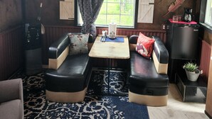 A cozy cabin interior with a wooden ceiling, a dining table with chairs, a water dispenser, and a refrigerator. - The Bunkhouse-within walking distance to Main Street Augusta (Augustaa)