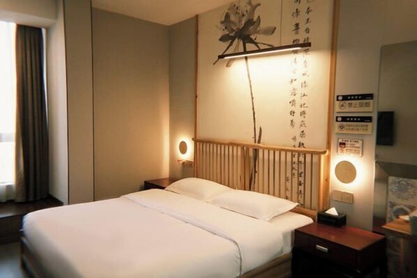 Ein Hotelzimmer mit Bett, Nachttischen, einer Wandlampe und einem dekorativen Gegenstand über dem Bett.