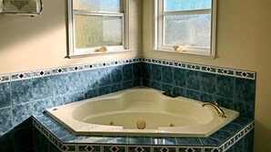 A bathroom with a freestanding bathtub, two windows with curtains, and a towel rack. - Star of the sea Guest house, Sea Forever King size bed with ocean view balcony! (White Rock)