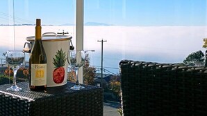 A bottle of wine and a wine cooler on a table in a room with a view of a snowy landscape. - Star of the sea Guest house, Sea Forever King size bed with ocean view balcony! (White Rock)