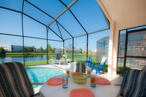 Un espace extérieur abrité comprenant une piscine, des sièges et une vue sur un terrain de golf.