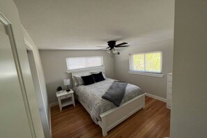 A bedroom with a bed, nightstand, and a ceiling fan.