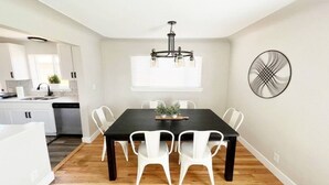 A dining area with a dark wooden table and white chairs, a chandelier, and a wall-mounted fan. - 3 Bedroom, Open Layout - Walk to Anschutz Medical! (Aurora)