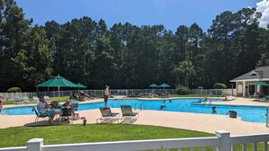 A swimming pool area with multiple pools, lounge chairs, and umbrellas. - True Blue Comfy Condo! (Pawleys Island)