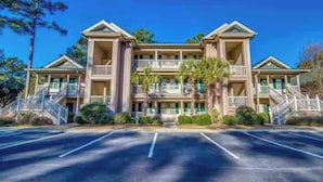 A multi-story hotel with a symmetrical facade, multiple balconies, and a central entrance. - True Blue Comfy Condo! (Pawleys Island)