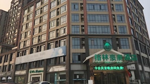 A multi-story building with a green sign indicating a hotel. - Greentree Inn (Suqian)