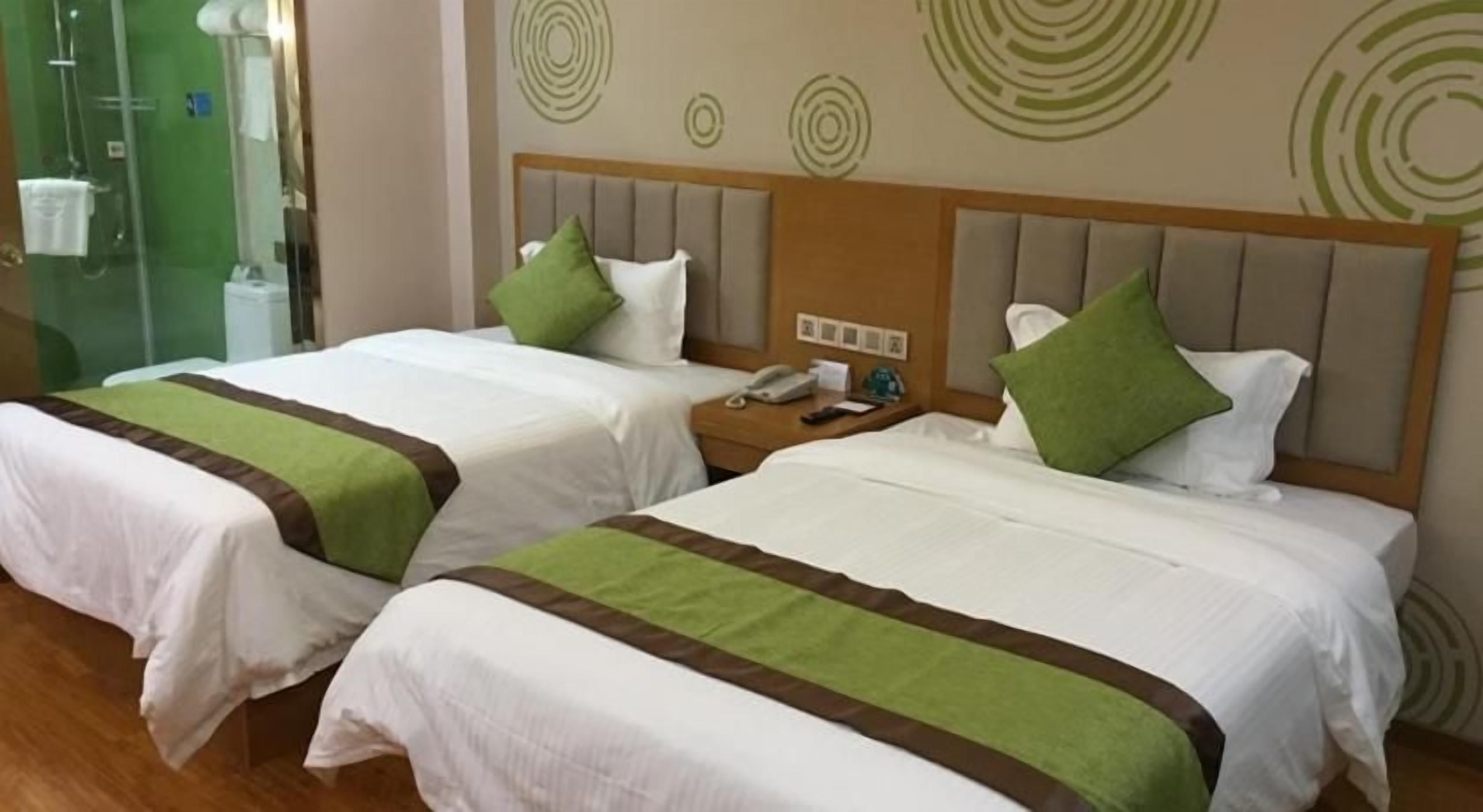 Two twin beds with green and brown bedspreads, a wooden headboard, and a nightstand with a phone.