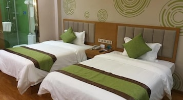 Two twin beds with green and brown bedspreads, a wooden headboard, and a nightstand with a phone.