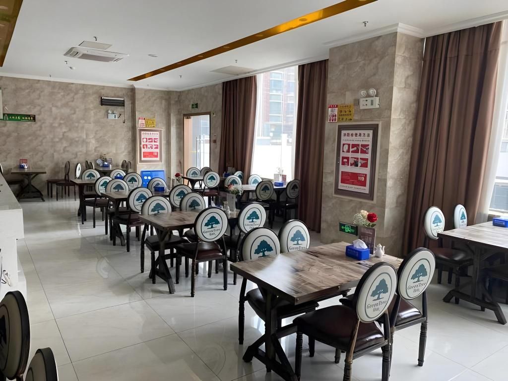 A dining area with multiple tables and chairs, some with logos, and a few posters on the walls.