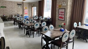 A dining area with multiple tables and chairs, some with logos, and a few posters on the walls. - Greentree Inn (Suqian)