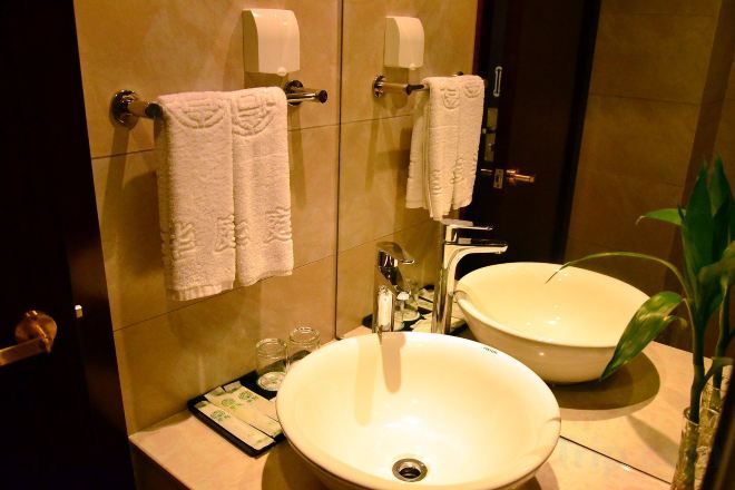 A bathroom with a large sink, two towel dispensers, and a mirror.