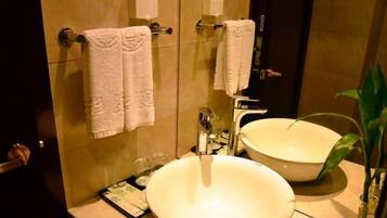 A bathroom with a large sink, two towel dispensers, and a mirror.