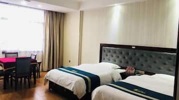A hotel room with two beds, a dining area, and a window with curtains.