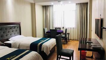 A hotel room with two beds, a desk, a chair, a TV, and a window with curtains.
