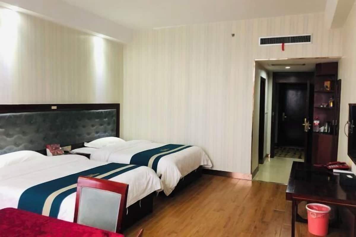 Ein Hotelzimmer mit zwei Betten, einem Schreibtisch, einem Stuhl, einem Fernseher und einem roten Eimer.