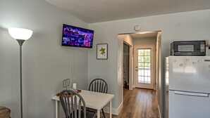 Una cocina compacta con refrigerador, microondas y comedor con sillas y mesa.