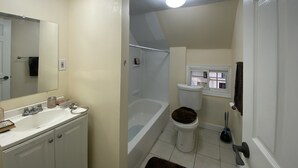 Ein Badezimmer mit Waschbecken, Spiegel, Toilette und Badewanne.