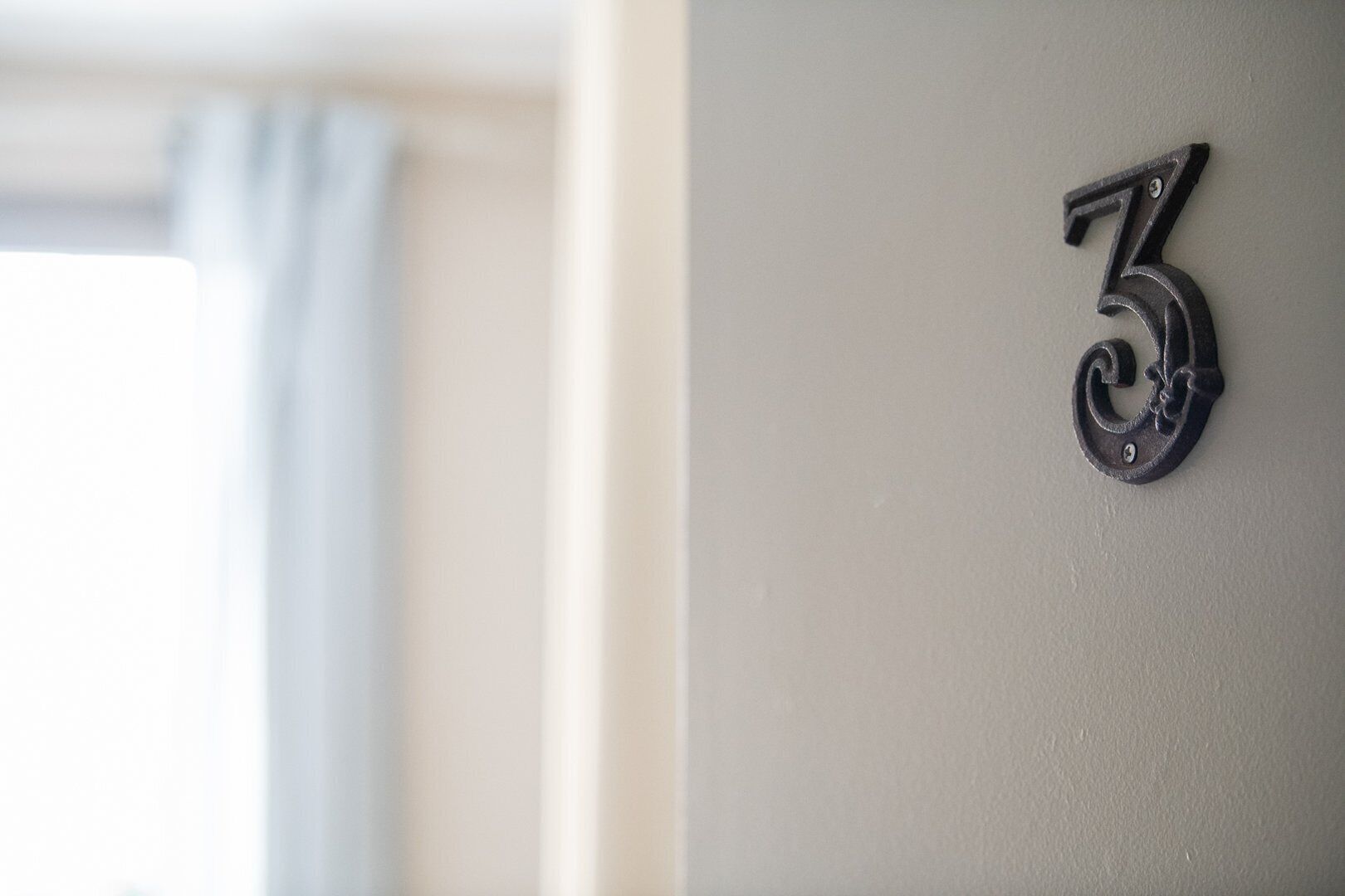 A close-up of a black metal number '3' mounted on a wall.