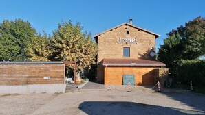 A two-story building with a sign reading "Jostel" and a smaller sign below it indicating a restaurant. - Le Jostel 2 (Genay)