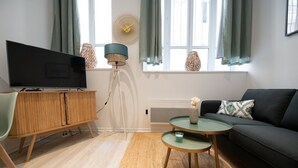 A modern living room with a television, wooden cabinet, and a sofa. - Opéra 2 - Lovely studio Hôtel de Ville (Lyon)