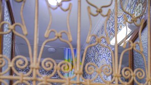 Un baño con barandillas de metal ornamentado, azulejos estampados y un lavabo blanco.