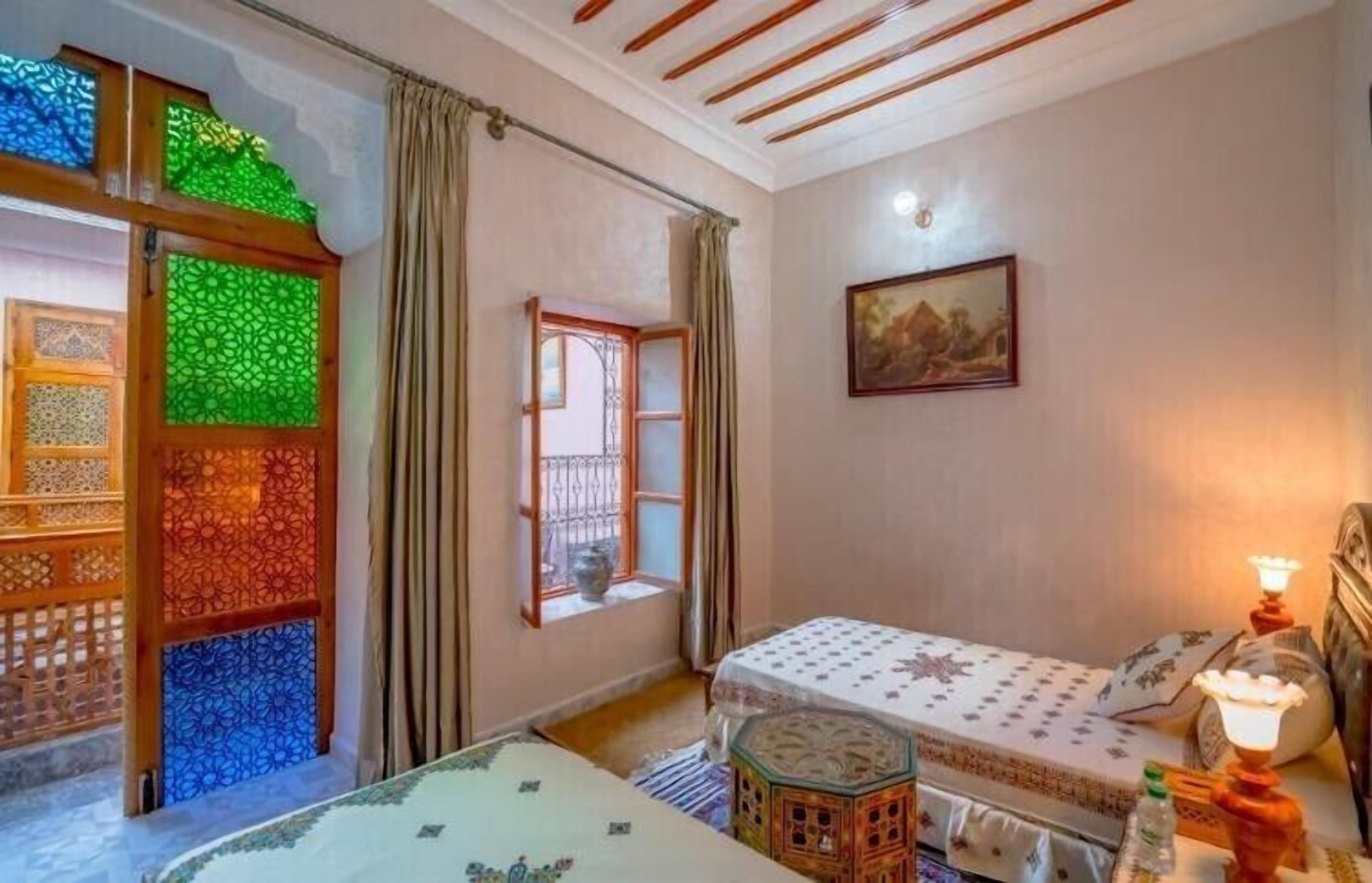 Quarto com cama, janela, pintura e um painel decorativo.